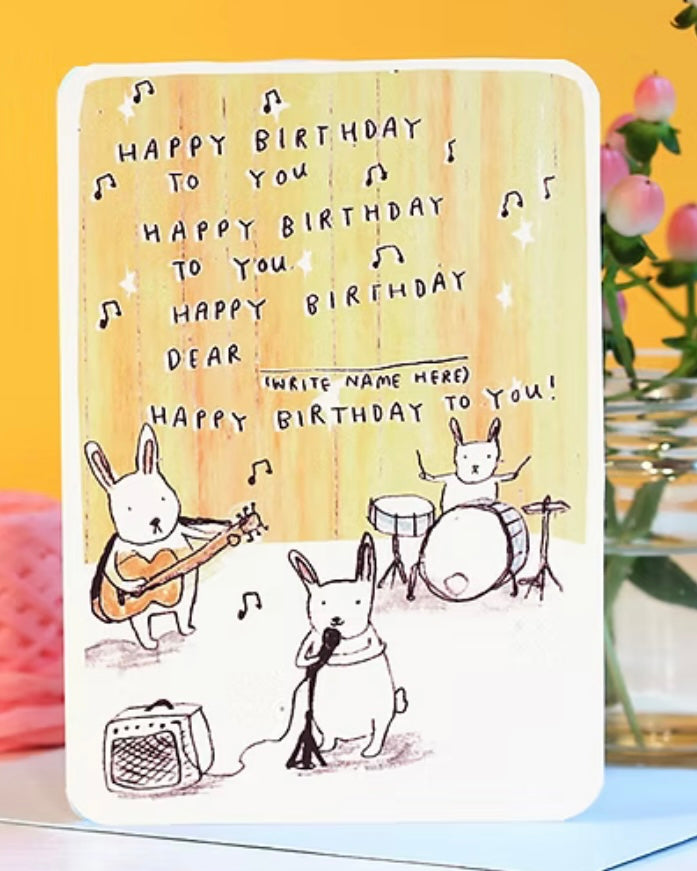 Birthday card with cartoon bunnies playing instruments on a yellow background