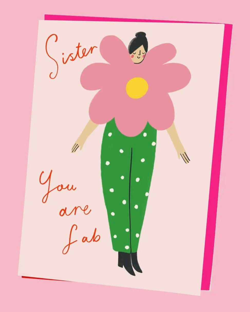 Greeting card with a stylised illustration of a person wearing a large pink flower on a pink background and the words Sister You Are Fab