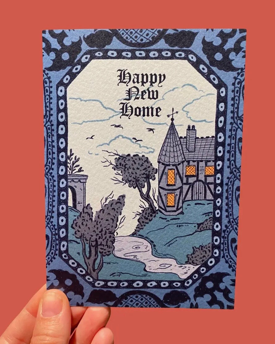 Greeting card with 'Happy New Home' text and gothic/haunted house illustration on a decorative border. 