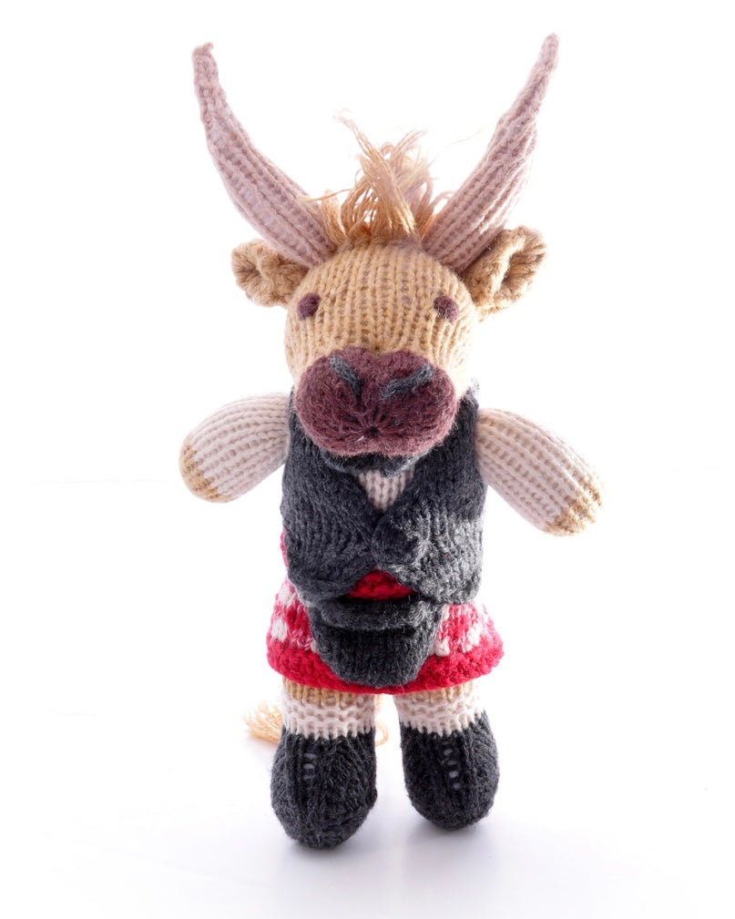 Knitted toy highland cow with a waistcoat and kilt, on a white background