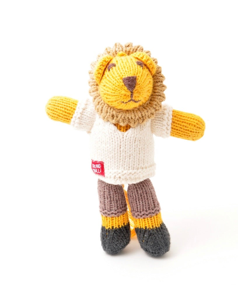 A hand-knitted lion doll with a yellow face and mane, wearing an off-white shirt, brown and gray striped pants, and yellow-and-gray boots, shown against a plain white background.