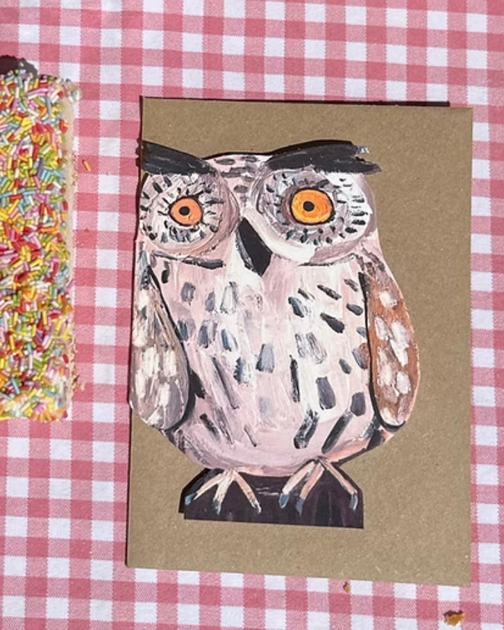 Shaped card with an owl illustration, with a brown kraft envelope, on a red and white checkered background
